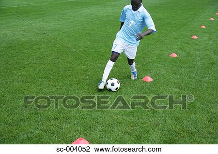 Soccer player dribbling through cones View Large Photo Image Stock Image - Soccer player dribbling through cones. Fotosearch