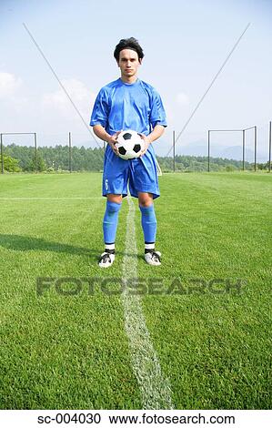 Stock Image - Soccer player holding ball on touchline. Fotosearch