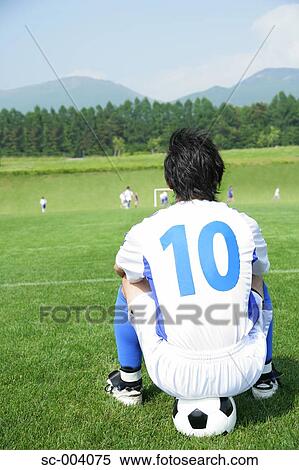Stock Photography - Soccer player sitting on ball. Fotosearch
