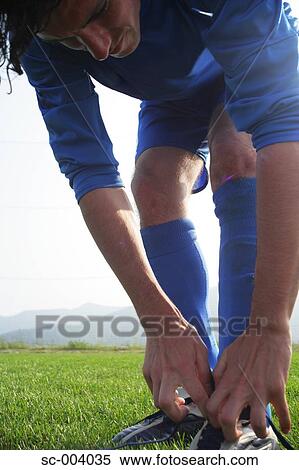 Stock Photography - Soccer player tying boot laces. Fotosearch