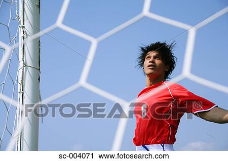 Stock Image - Soccer player viewed through goalnet. Fotosearch