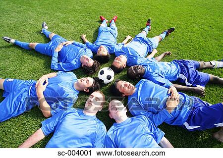 Stock Image - Soccer players lying down around a ball. Fotosearch