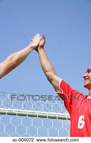 Stock Image - Team mates give each other a high-five. Fotosearch