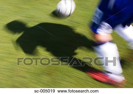 Stock Photo - Shadow of soccer player running with ball. Fotosearch