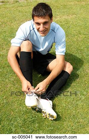 Stock Image - Soccer player tying boot laces. Fotosearch