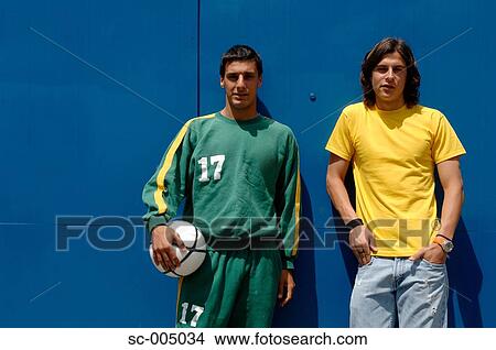 Picture - Young friends with soccer ball in front of blue gate. Fotosearch