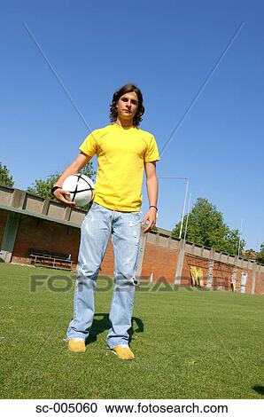 Young man in casual wear holding soccer ball View Large Photo Image Stock Image - Young man in casual wear holding soccer ball. Fotosearch