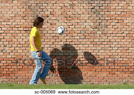 Young man juggling soccer ball in front of brick wall View Large Photo Image Stock Photo - Young man juggling soccer ball in front of brick wall. Fotosearch