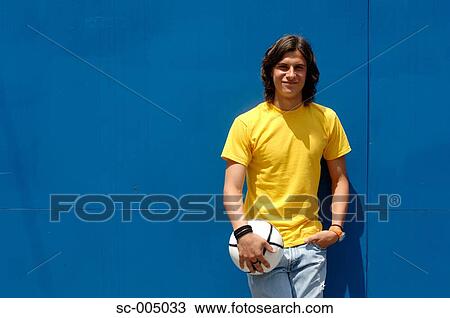 Young man leaning against blue gate and holding ball View Large Photo Image Stock Image - Young man leaning against blue gate and holding ball. Fotosearch