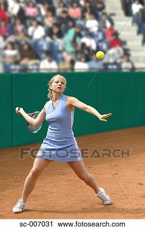 Stock Image - Female Tennis Player Hitting Ball. Fotosearch