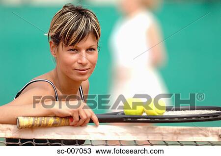 Stock Image - Female Tennis Player Leaning on Net. Fotosearch