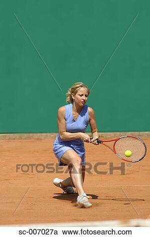 Stock Image - Front View of Female Tennis Player Hitting Ball. Fotosearch
