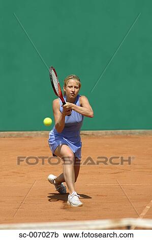 Stock Image - Front View of Female Tennis Player Hitting Ball. Fotosearch