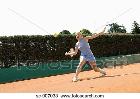 Stock Image - Front View of Female Tennis Player Hitting Ball. Fotosearch