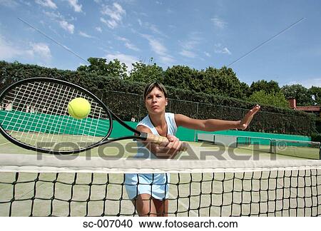 Stock Image - Front View of Female Tennis Player Hitting Ball. Fotosearch