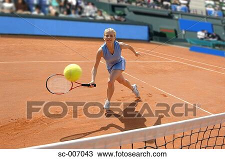 Stock Image - Front View of Female Tennis Player Hitting Ball. Fotosearch