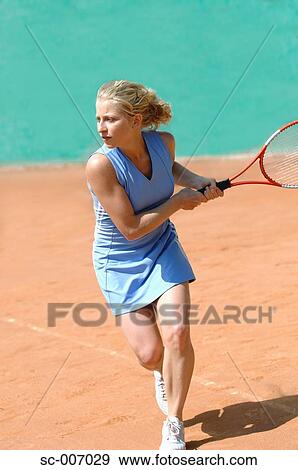 Stock Photo - Side View of Female Tennis Player Hitting Ball. Fotosearch