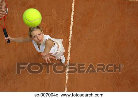 Stock Image - Top View of Female Tennis Player Mid-Serve. Fotosearch