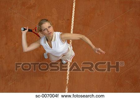 Stock Image - Top View of Female Tennis Player Mid-Serve. Fotosearch