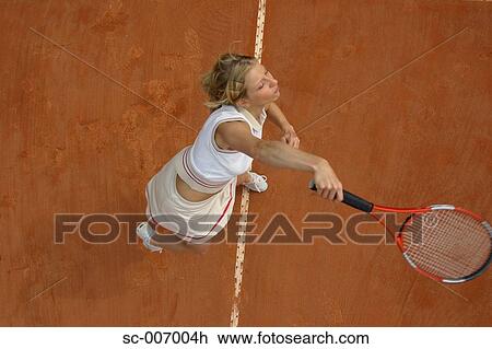 Stock Image - Top View of Female Tennis Player Mid-Serve. Fotosearch