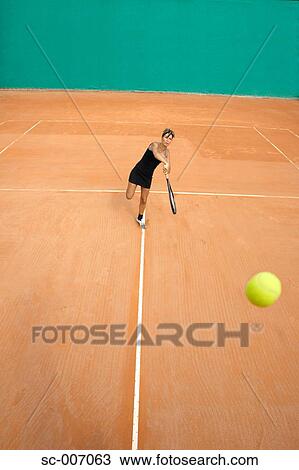 Stock Image - Wide Shot of Female Tennis Player on Clay Court. Fotosearch