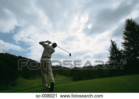 A man swings a golf club against a dramatic sky View Large Photo Image Stock Image - A man swings a golf club against a dramatic sky. Fotosearch