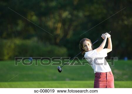 A young woman makes a stroke with a golf club View Large Photo Image Stock Photo - A young woman makes a stroke with a golf club. Fotosearch