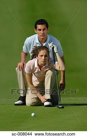Picture - Couple lining up a putt on the green. Fotosearch
