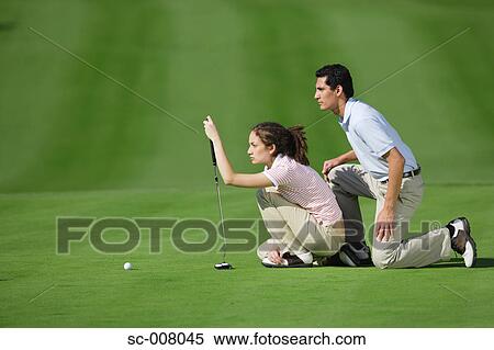 Couple lining up a putt on the green View Large Photo Image Stock Photography - Couple lining up a putt on the green. Fotosearch