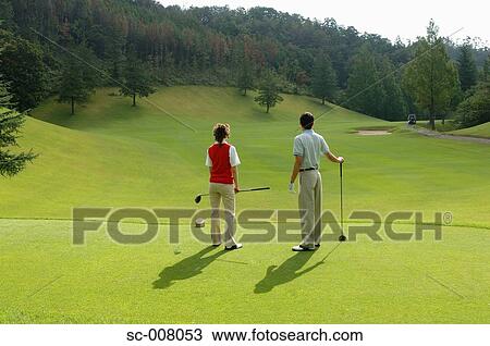 Stock Image - Couple looking down the fairway from the tee ground. Fotosearch