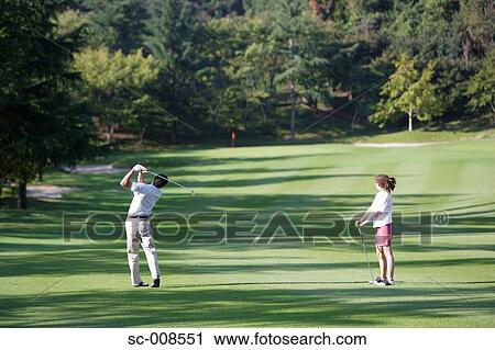 Stock Image - Couple Playing Golf on a Golf Course. Fotosearch