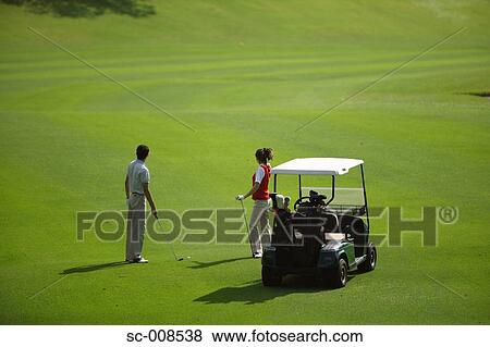 Stock Photo - Couple Standing by a Golf Cart on a Fairway. Fotosearch