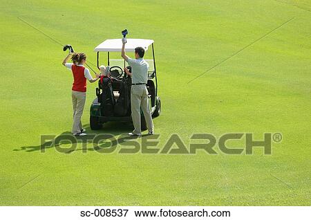 Couple Taking Clubs Out of a Golf Cart View Large Photo Image Stock Photo - Couple Taking Clubs Out of a Golf Cart. Fotosearch