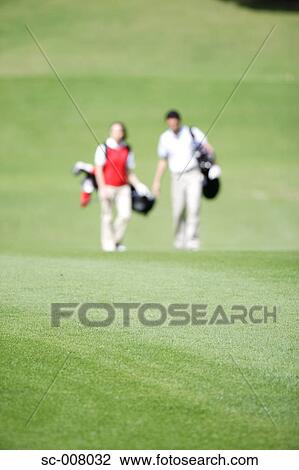 Couple walking on the fairway carrying their golf bags View Large Photo Image Stock Image - Couple walking on the fairway carrying their golf bags. Fotosearch