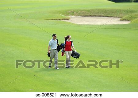 Stock Image - Couple Walks Down the Fairway of a Golf Course. Fotosearch