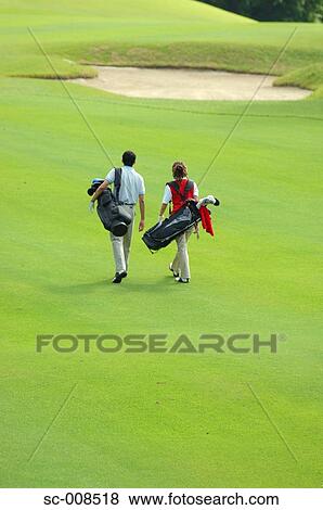 Stock Photo - Couple Walks Down the Fairway of a Golf Course. Fotosearch
