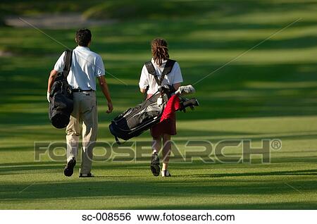 Stock Photograph - Couple Walks Down the Fairway of a Golf Course. Fotosearch