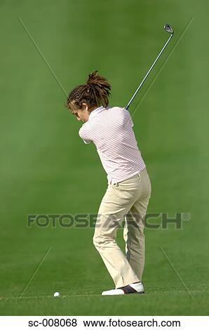 Stock Photo - Female golfer in action on the fairway. Fotosearch
