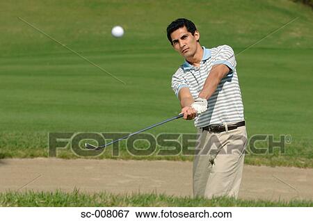 Stock Photo - Front view of a man playing a bunker shot. Fotosearch