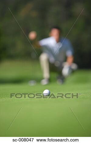 Golf ball in foreground as man lines up a putt View Large Photo Image Stock Photo - Golf ball in foreground as man lines up a putt. Fotosearch