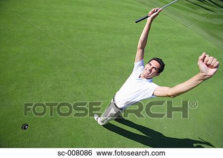 Stock Photograph - Male golfer clenching his fists in excitement after a making a putt. Fotosearch