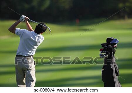 Picture - Male golfer hitting towards the green. Fotosearch