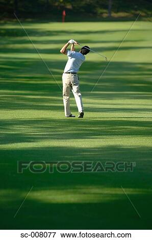 Stock Photo - Male golfer hitting towards the green. Fotosearch