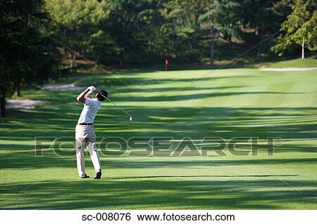 Stock Photograph - Male golfer hitting towards the green. Fotosearch