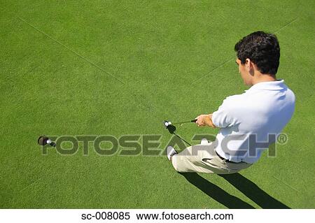 Stock Photography - Male golfer making a putt. Fotosearch