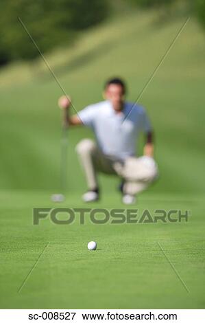 Stock Photo - Man Looking at a Golf Ball on a Putting Green. Fotosearch