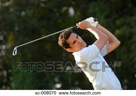 Stock Image - Portrait of a man in action holding a golf club. Fotosearch