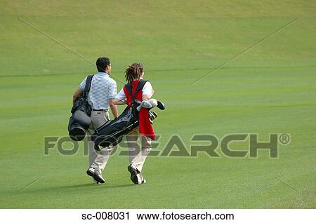 Rear view of a couple walking on the fairway as they carry their golf bags View Large Photo Image Stock Image - Rear view of a couple walking on the fairway as they carry their golf bags. Fotosearch