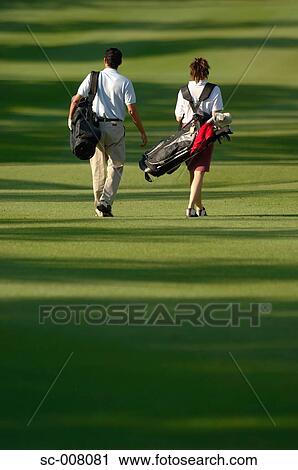 Rear view of a couple walking on the fairway as they carry their golf bags View Large Photo Image Stock Image - Rear view of a couple walking on the fairway as they carry their golf bags. Fotosearch