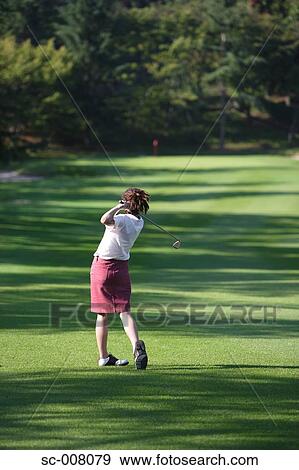Rear view of a female golfer playing a shot View Large Photo Image Stock Photo - Rear view of a female golfer playing a shot. Fotosearch